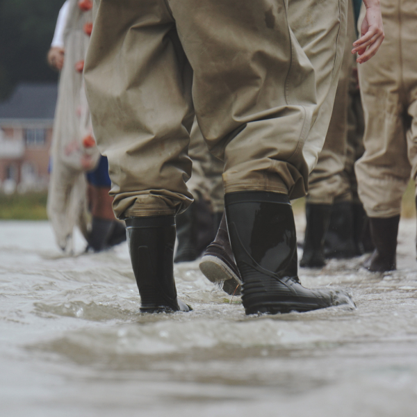 Several people in rain boots standing in a flooded street