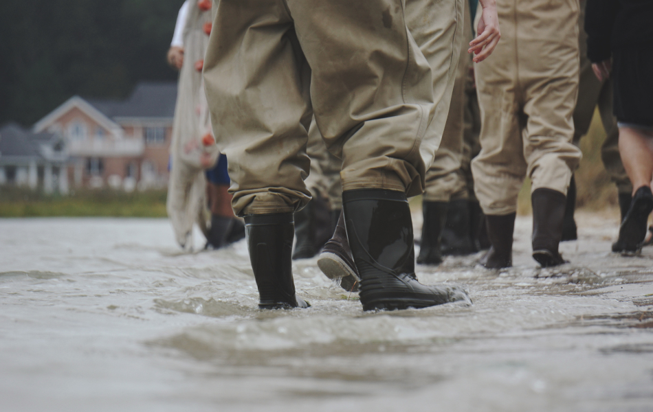 Several people in rain boots standing in a flooded street